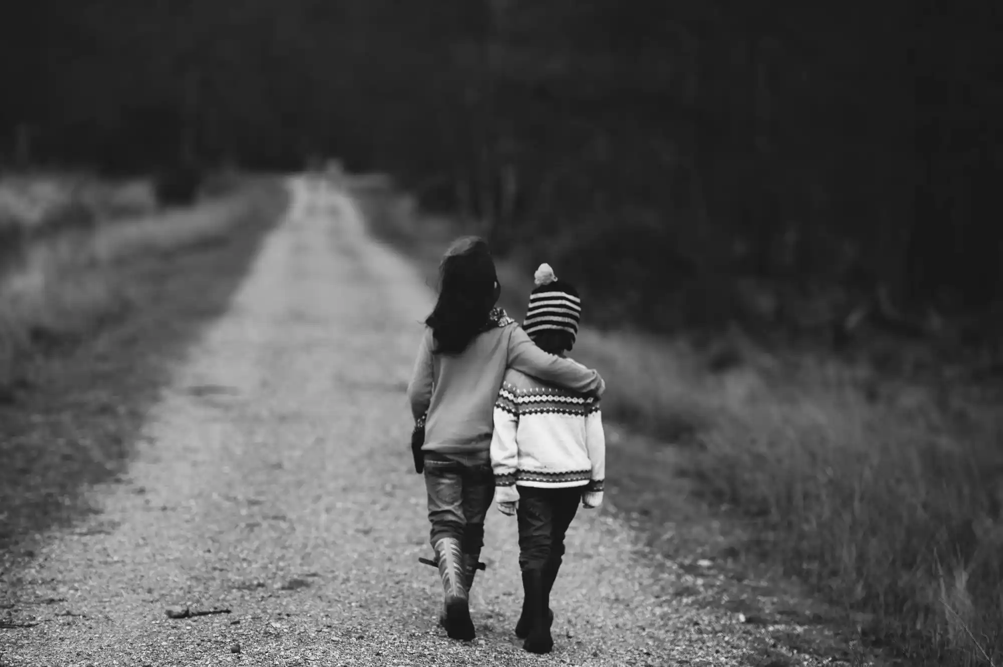 Two children walking arm in arm on a path
